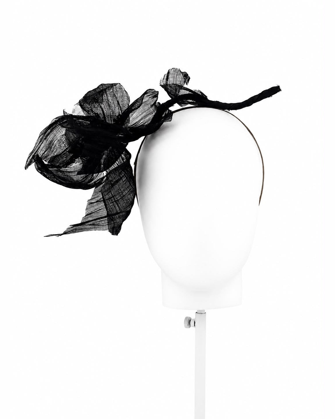 Black abaca flower headband on a display head, the flower set to the wearer's right, Maria Monica London