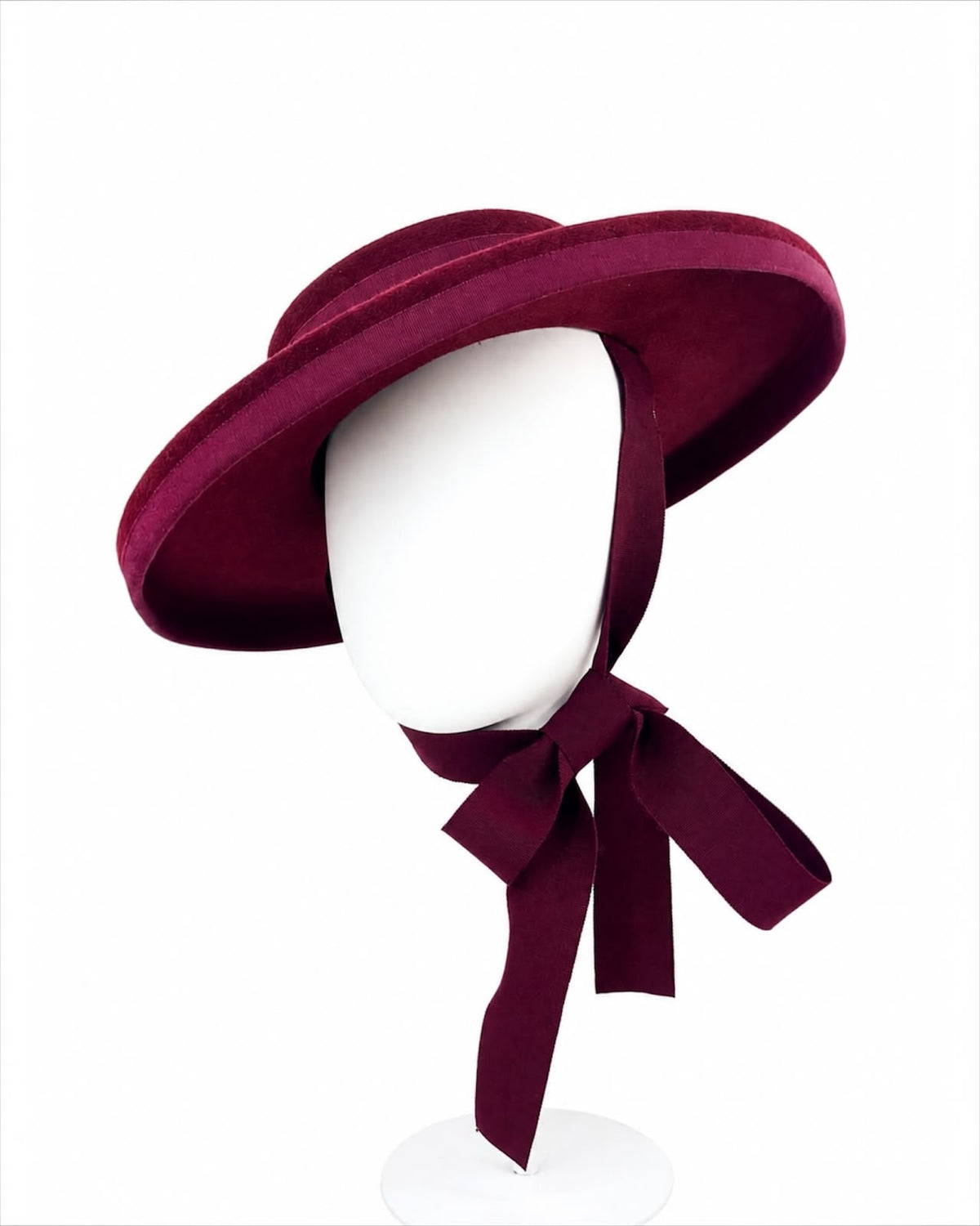 Claret oversized felt boater worn on a head block with grosgrain ties tied in a bow under the chin, Maria Monica London