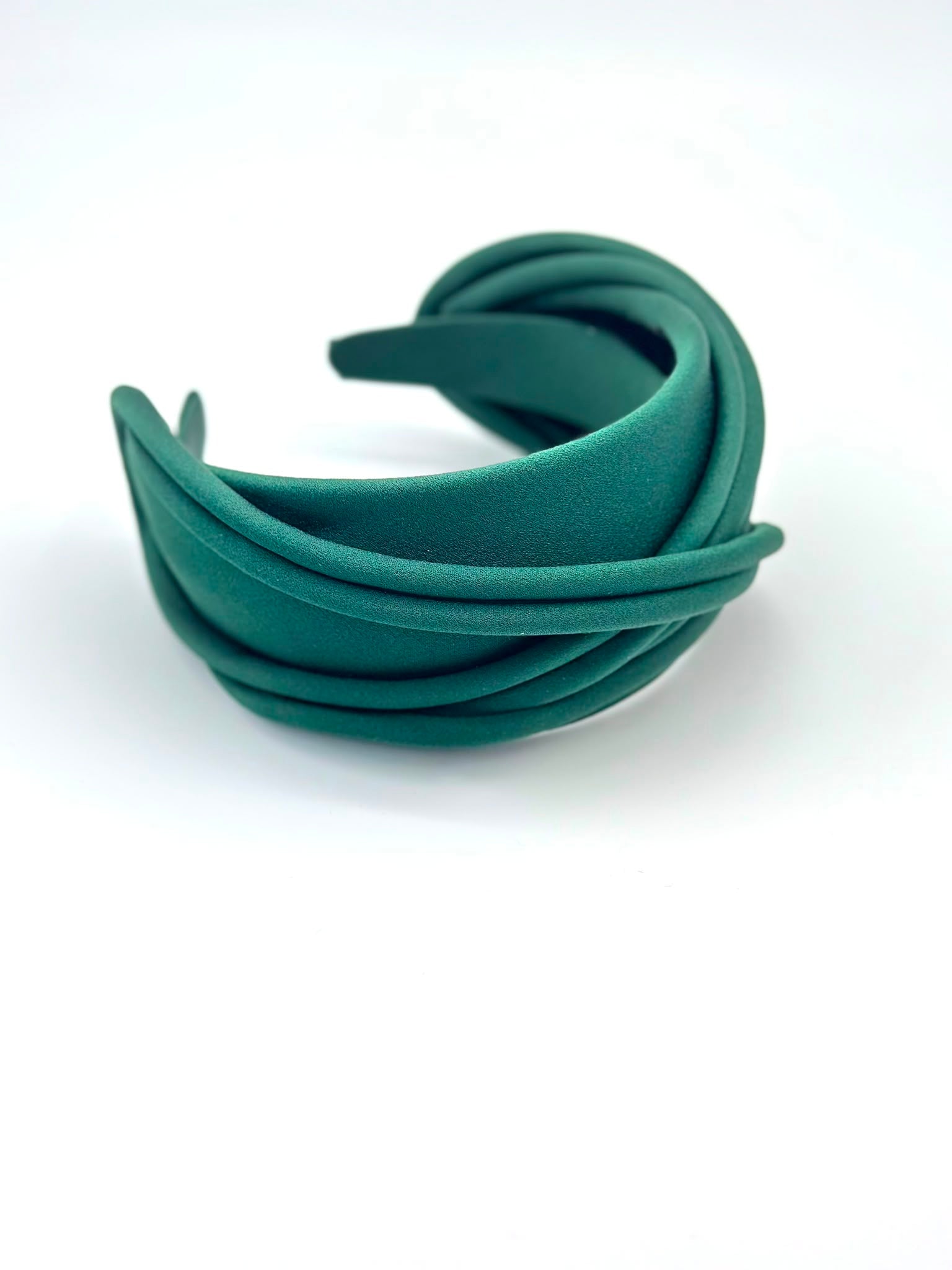 Emerald green satin headband built from crossed satin piping, shown at an angle, Maria Monica London