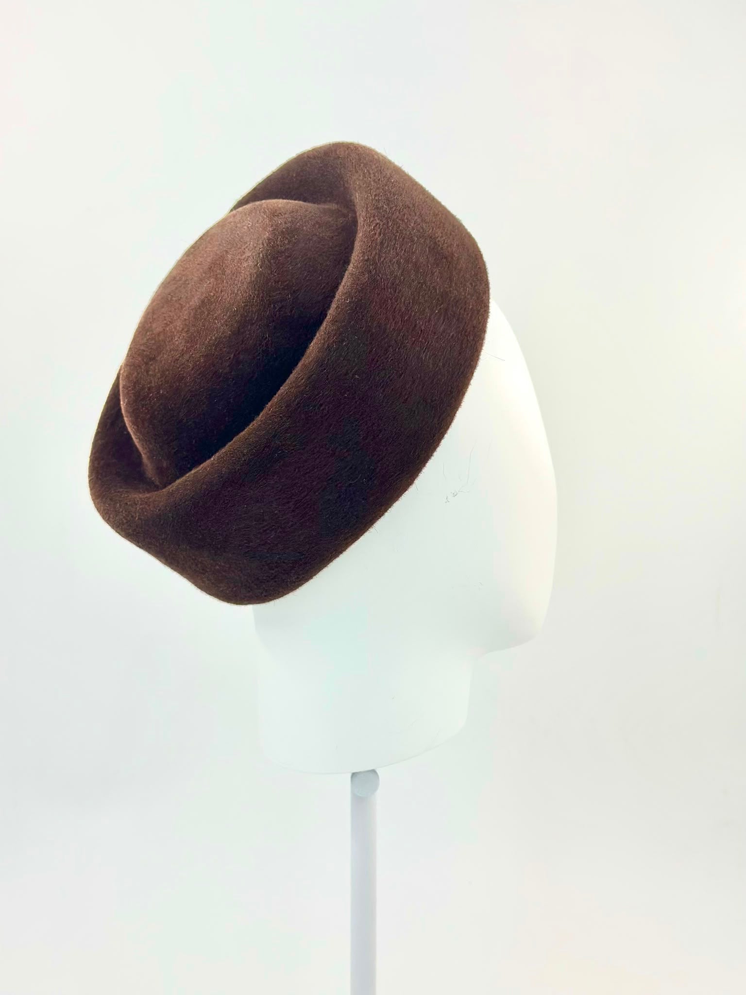 Espresso brown felt Jackie-style pillbox hat worn on a stand, handmade in London by Maria Monica London