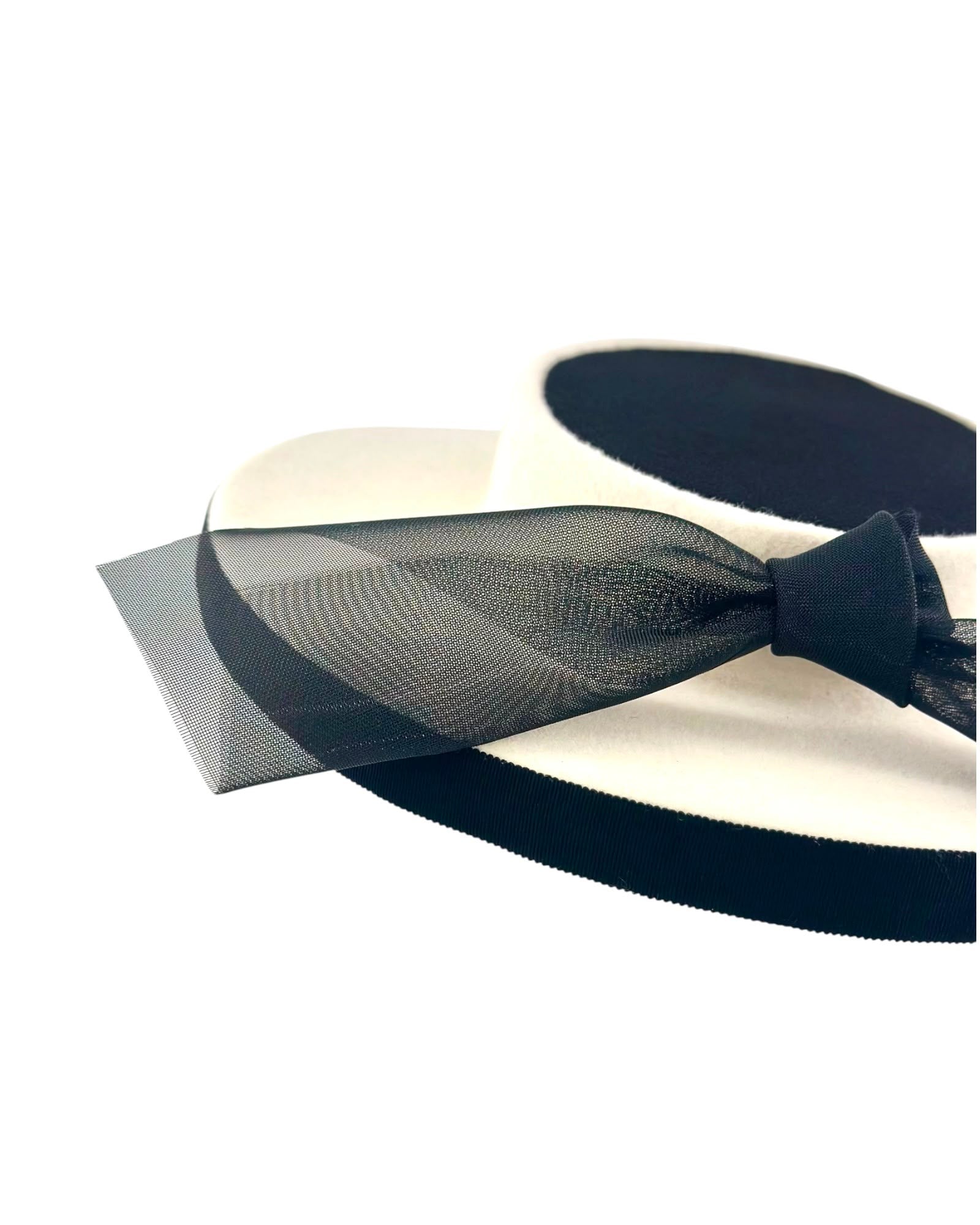 Close view of the black crinoline bow knot and the black grosgrain edging on the ivory felt boater, Maria Monica London