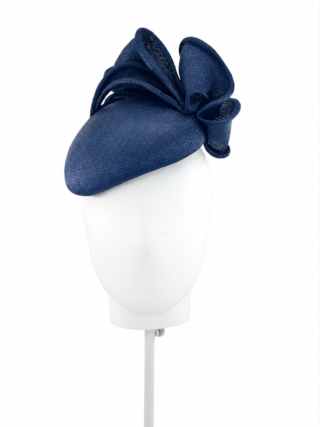 Midnight navy parasisal cocktail hat with a hand-sculpted straw bow, shown on a display head, Maria Monica London