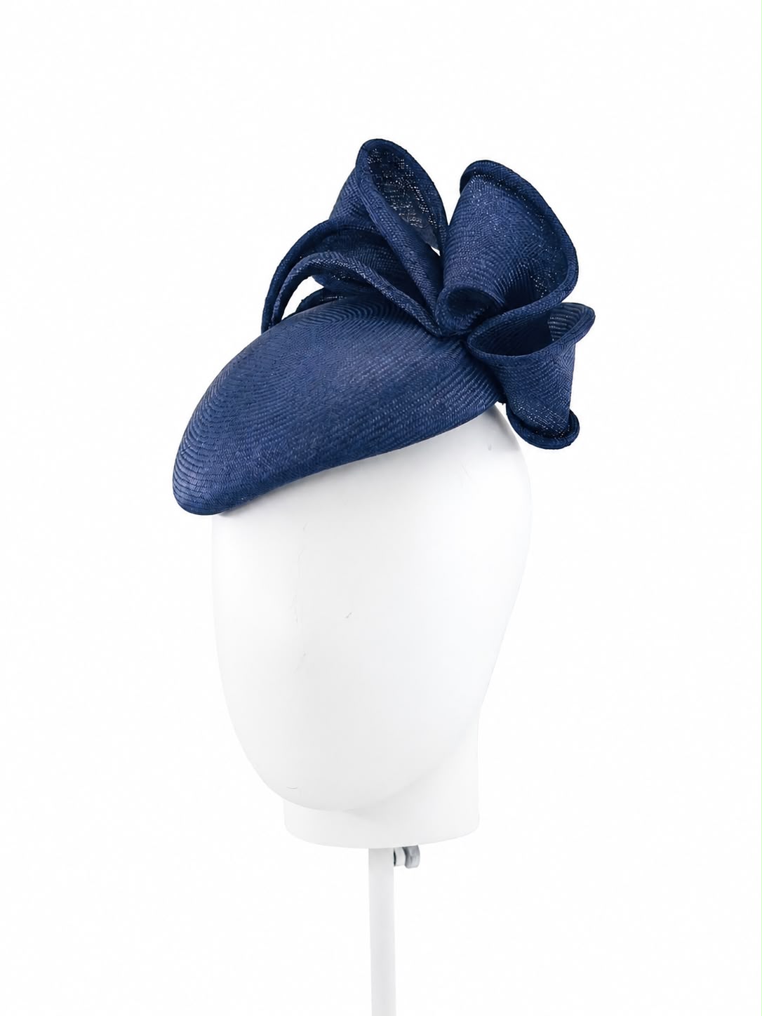 Midnight navy parasisal cocktail hat with a looped straw bow, angled on a white display head, Maria Monica London