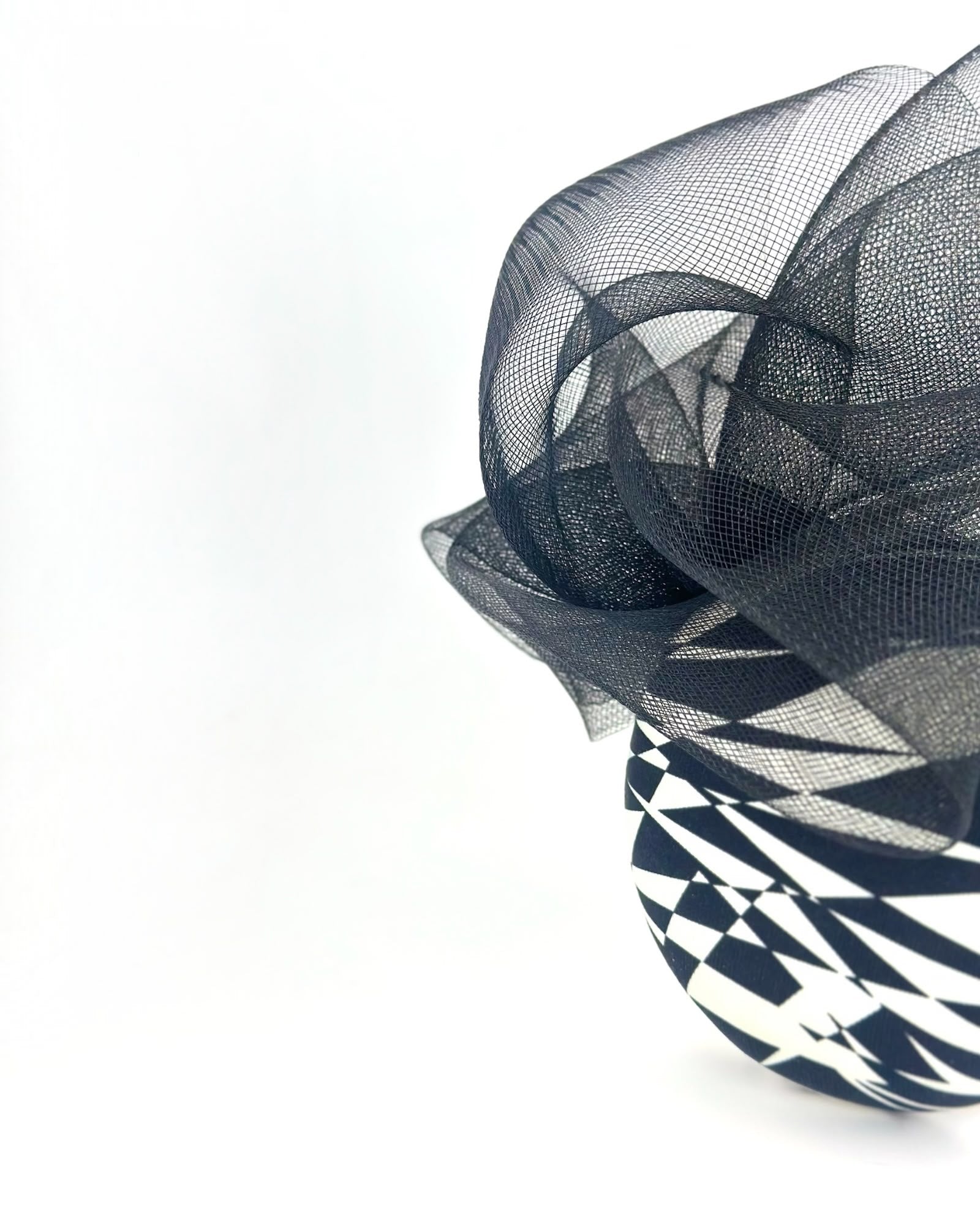 Close view of black crinoline swirling above a black and white geometric print silk crown, Maria Monica London