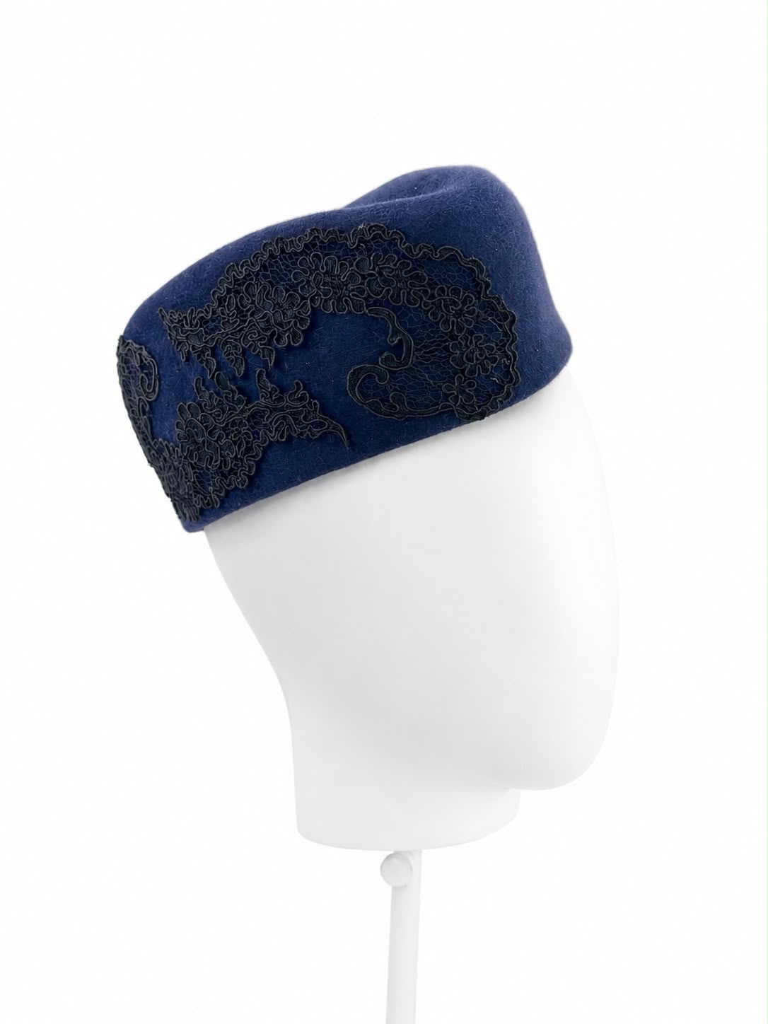 Navy felt sculptural pillbox hat with black lace worn on a stand, Maria Monica London
