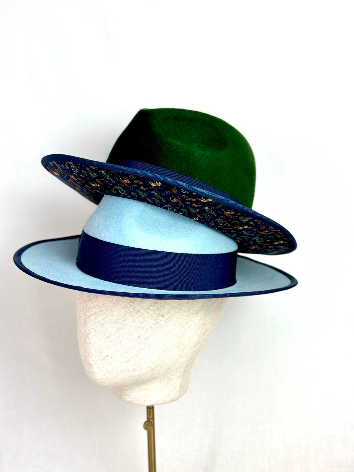 Powder blue and forest green fedoras with navy bands and a woodland print under the brim, Maria Monica London