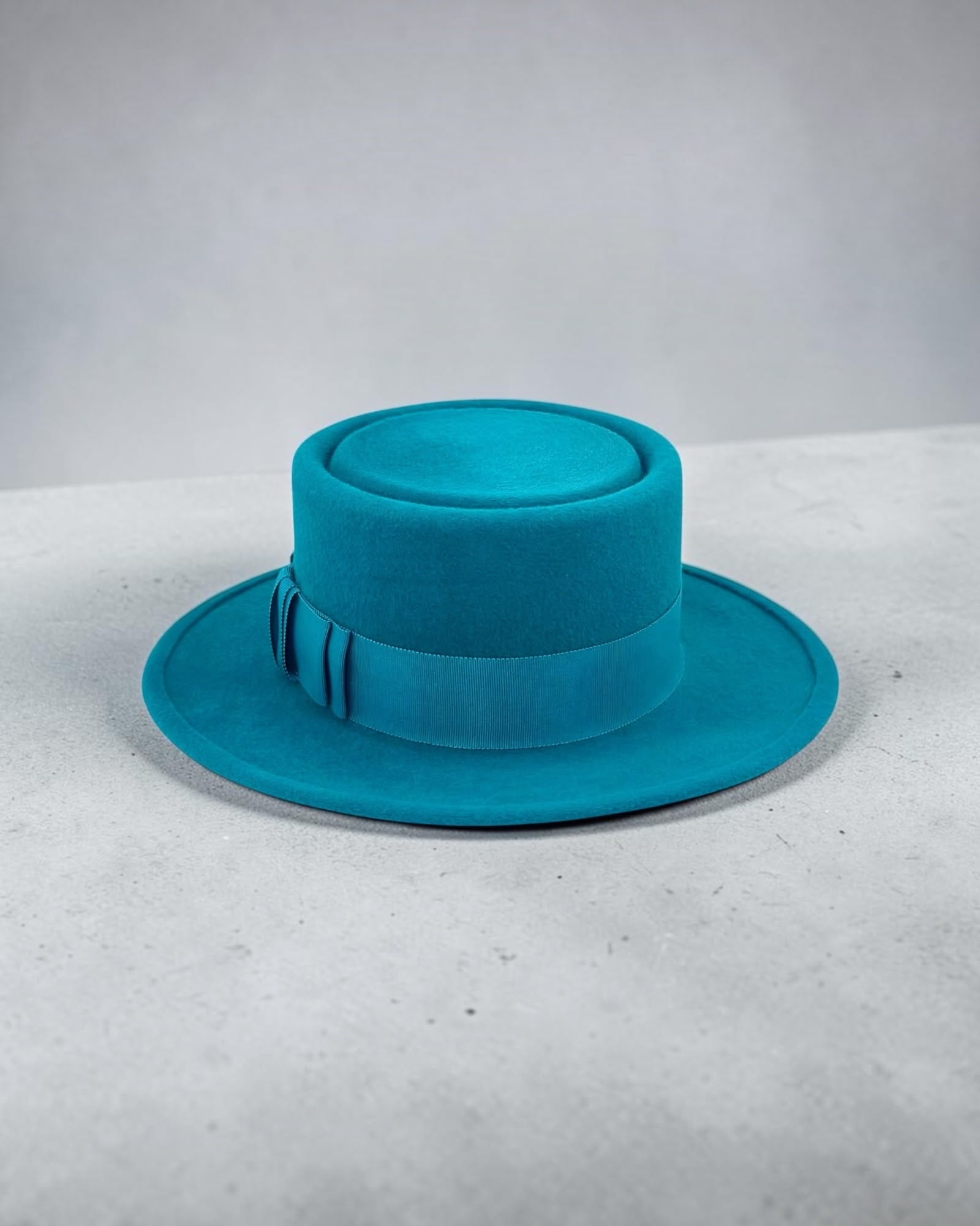 Close view of the hand-finished brim edge and invisible stitching on the turquoise felt boater, handmade in London