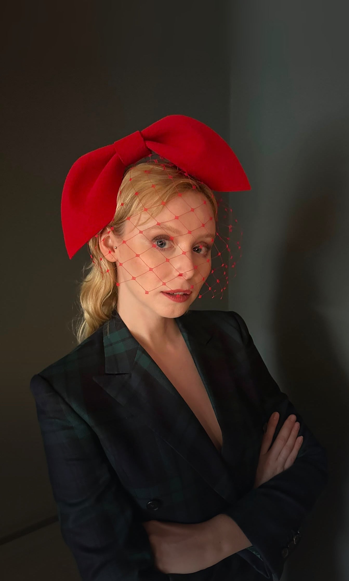 Model wearing the scarlet red sculpted felt bow headpiece with veil, Maria Monica London