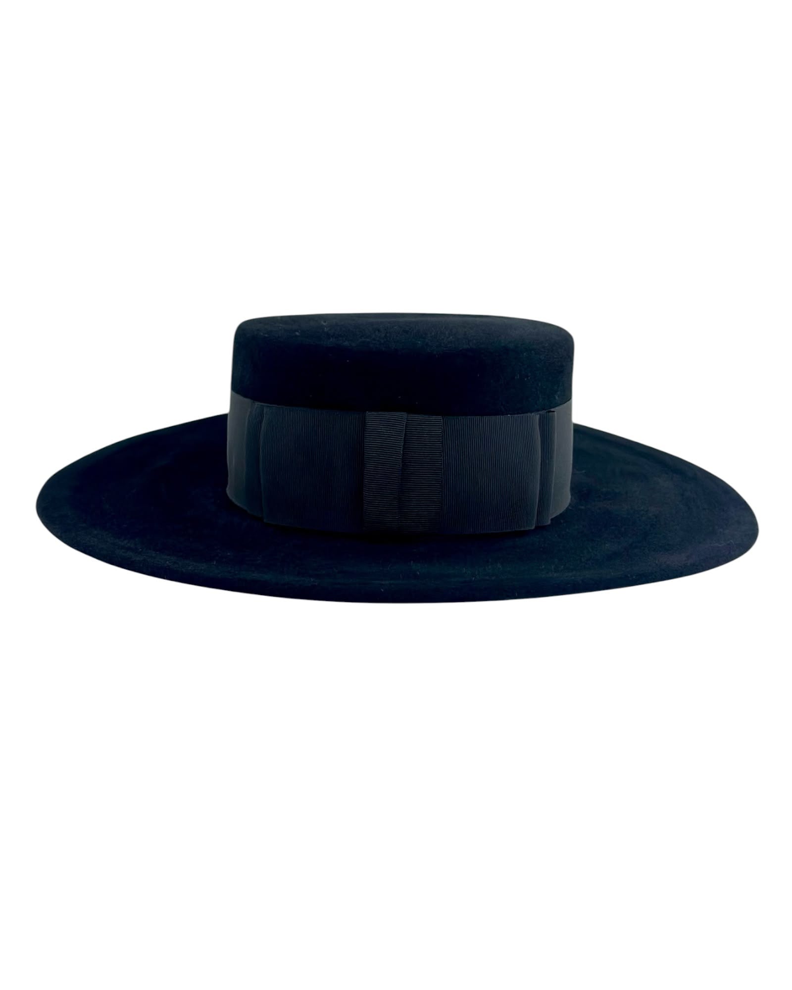 Front view of the black velvet felt boater showing the flat crown and the tonal grosgrain ribbon bow, handmade in London