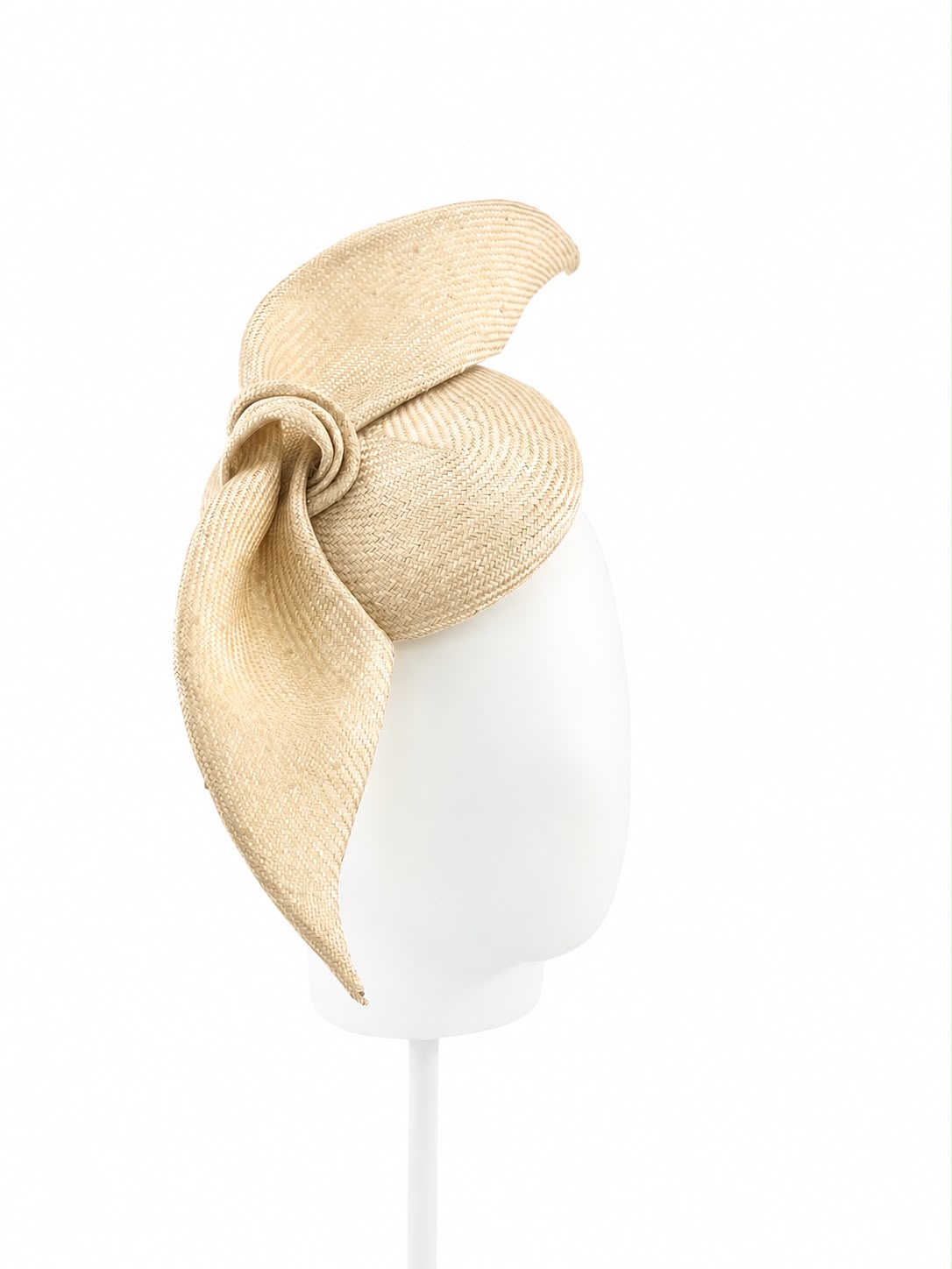 Champagne straw cocktail hat with a large sculpted bow, shown on a display head, Maria Monica London