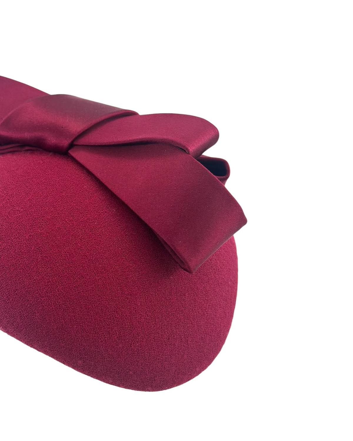 Close detail of the claret wool crêpe and satin silk bow on a cocktail hat handmade in London