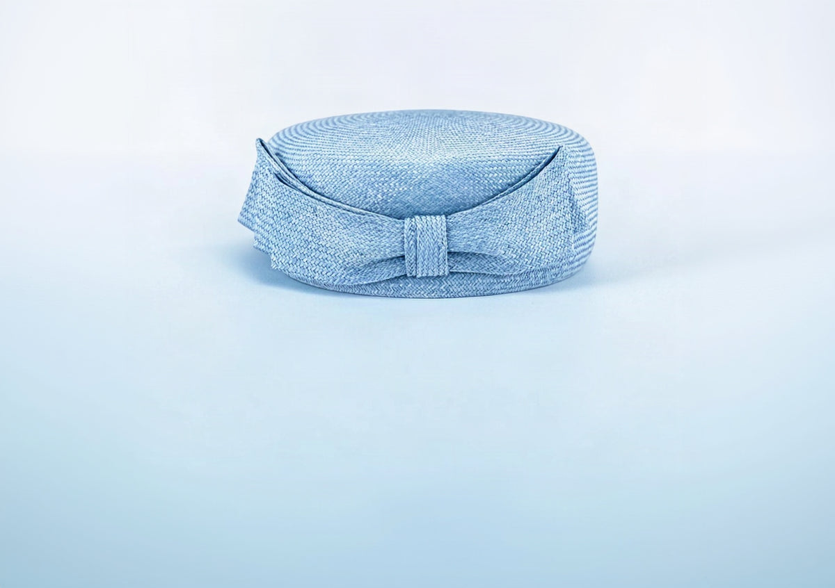 Ice blue parasisal straw pillbox hat with a straw bow at the front, Maria Monica London