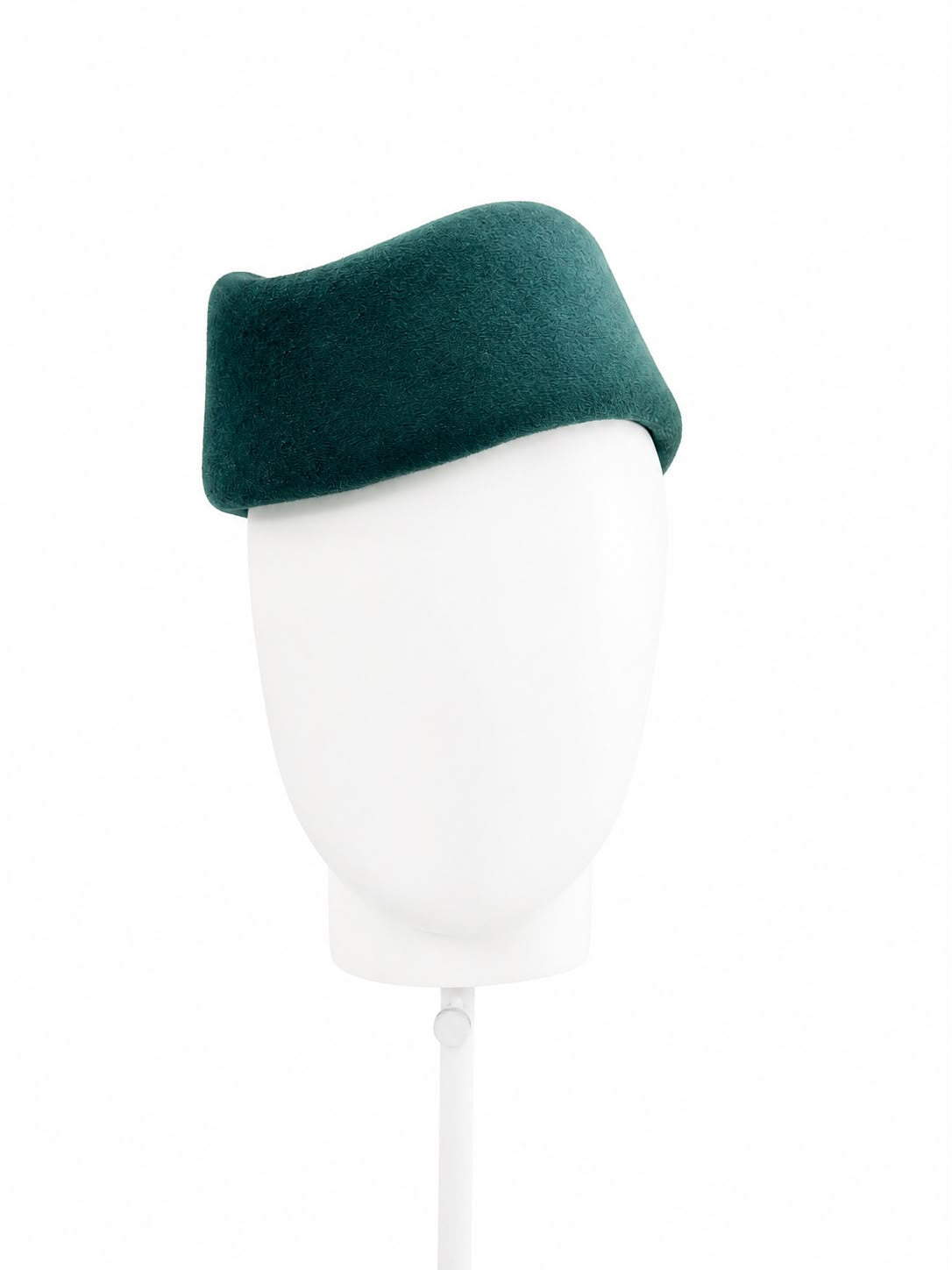 Deep teal wool felt sculptural pillbox hat worn on a stand, Maria Monica London