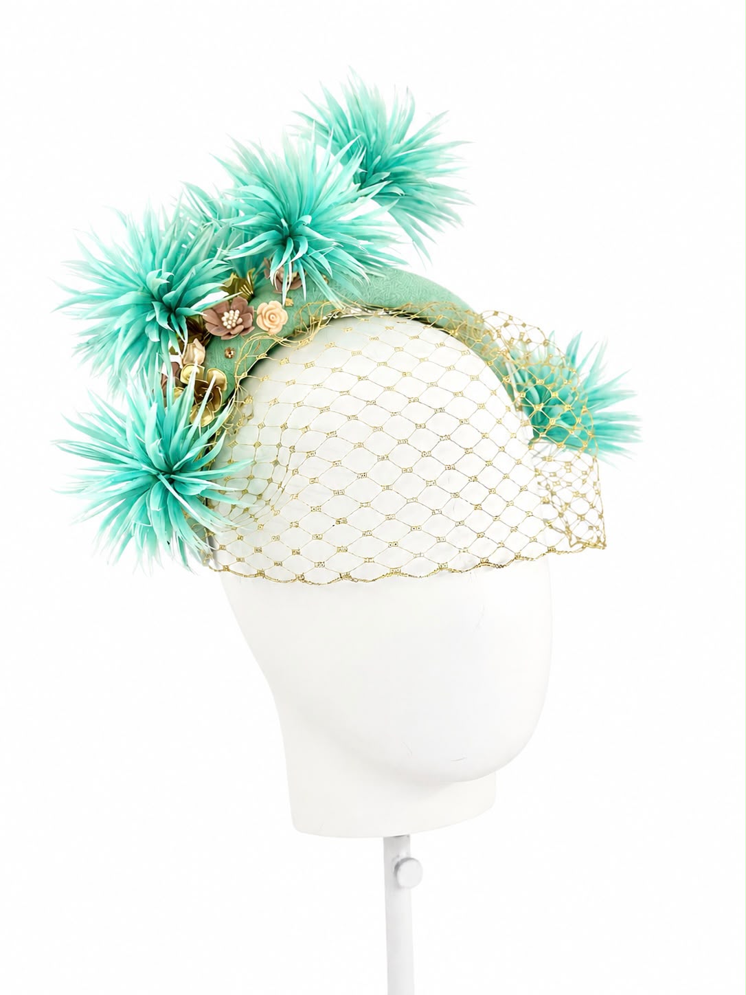 Aqua mint feather headband with a gold veil sweeping across the face, seen at an angle on a display head, Maria Monica London