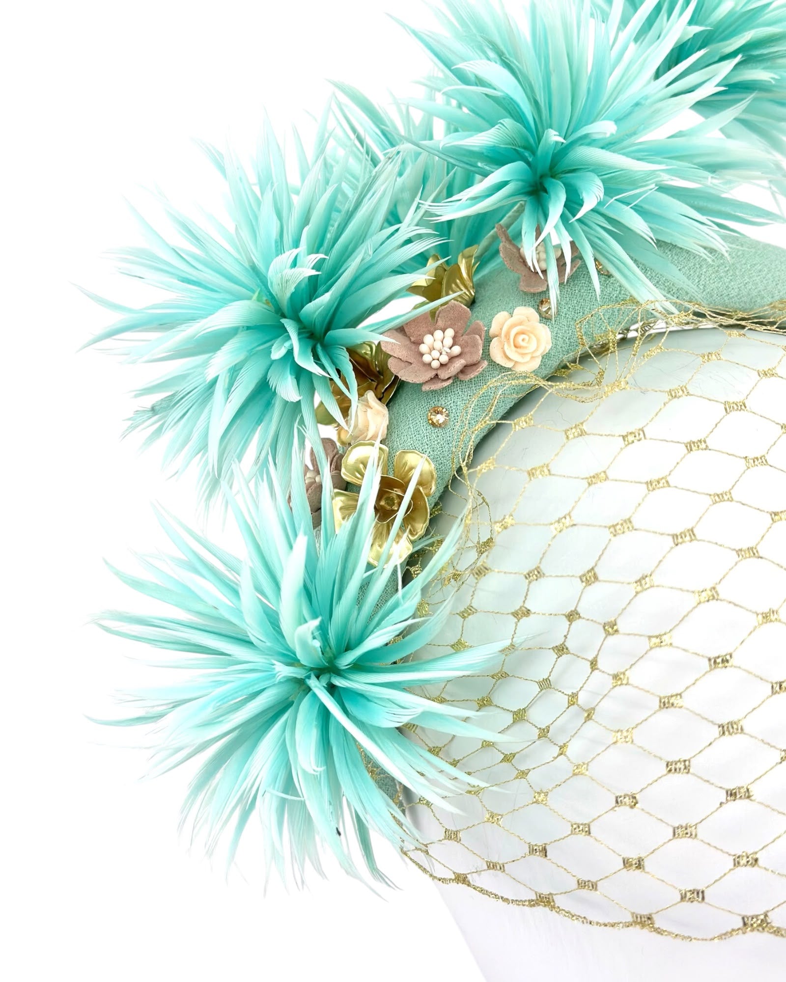 Close view of the sculpted aqua mint feather flowers, gold metal leaves and blush ceramic blooms above the gold veiling, Maria Monica London